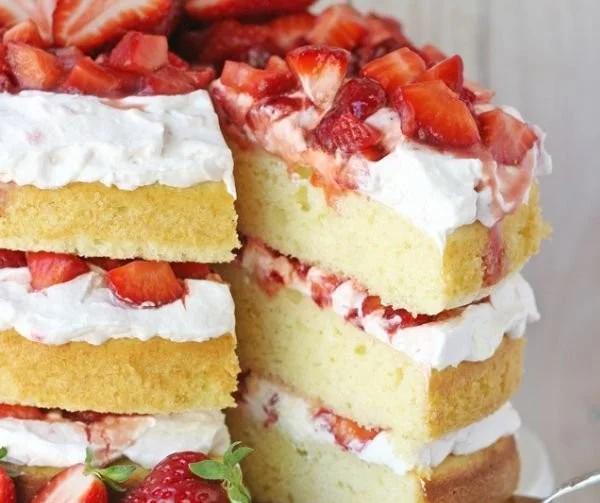 Slice of the best strawberry shortcake cake topped with fresh strawberries