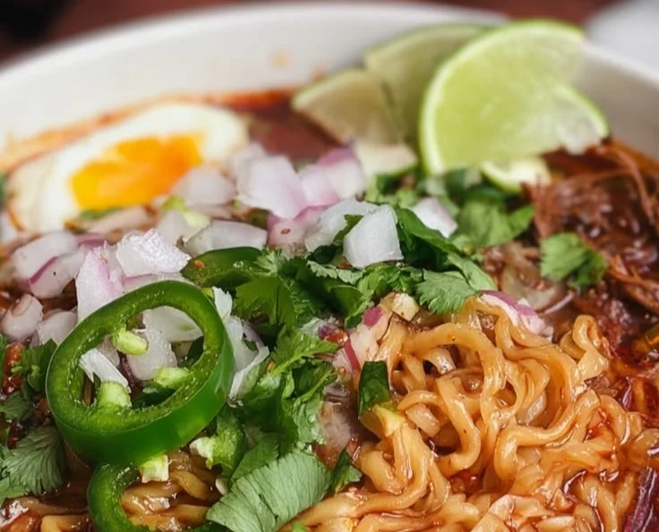 Bowl of Birria Ramen topped with fresh herbs and spicy broth