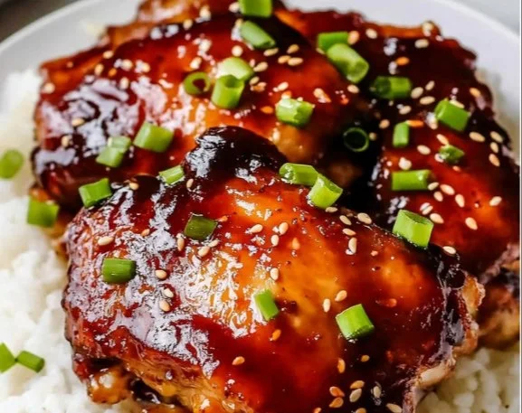 Slow cooker honey garlic chicken thighs in a bowl with green garnish