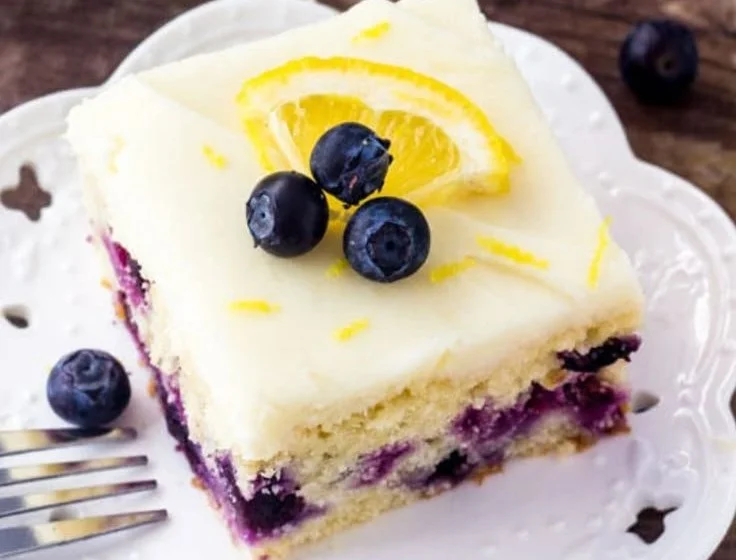 Slice of moist Lemon Blueberry Cake topped with blueberries and lemon zest