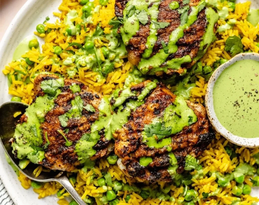 Plate of Peruvian Chicken and Rice with green sauce served on a rustic table.