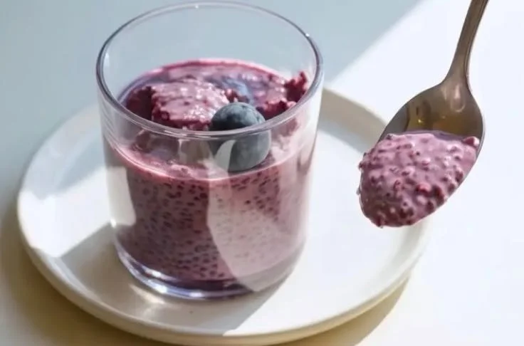 A bowl of blueberry chia seed pudding topped with fresh blueberries and mint