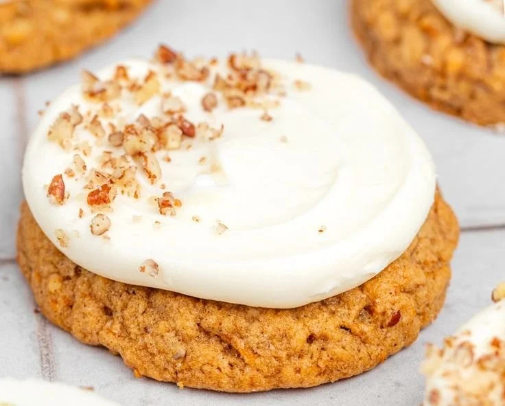 Delicious carrot cake cookies topped with cream cheese frosting on a plate.