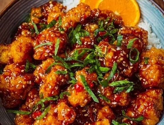 Delicious crispy orange chicken garnished with zesty sauce