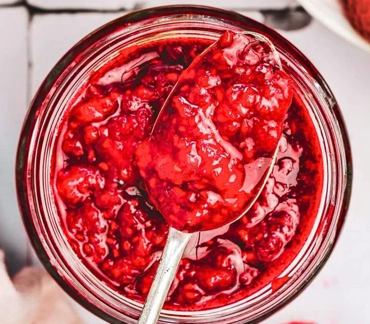 Easy raspberry compote served in a dish with fresh raspberries and mint sprig