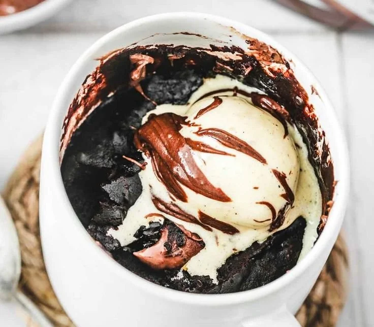Delicious Nutella Mug Cake in a ceramic mug, topped with chocolate and nuts.