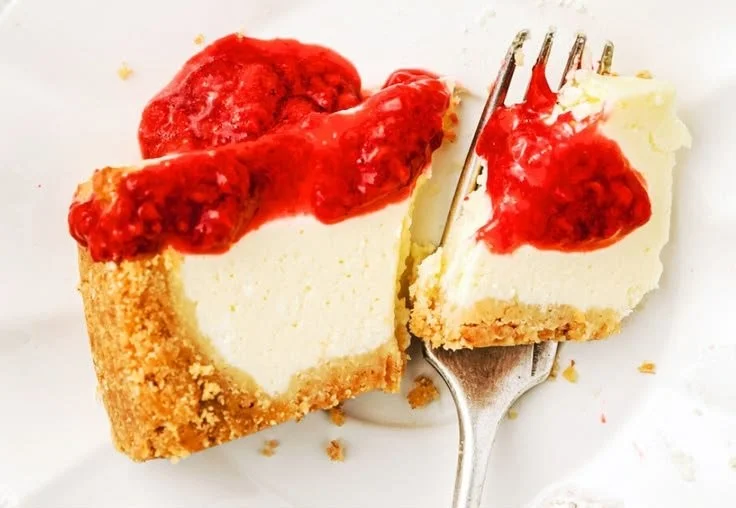 Homemade raspberry sauce drizzled over a slice of cheesecake