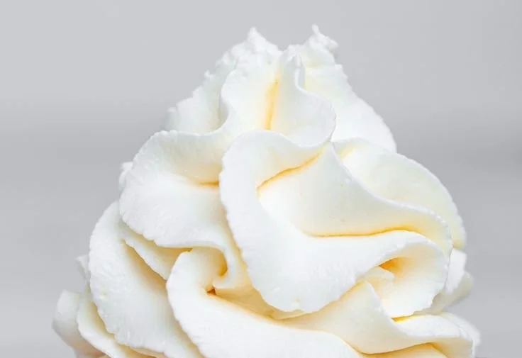Bowl of stabilized whipped cream frosting ready for cake decorating.