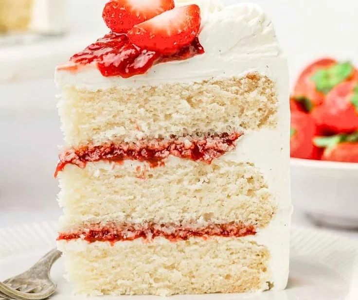 Delicious Strawberry Vanilla Cake topped with fresh strawberries and whipped cream.