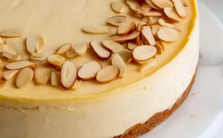 Delicious Amaretto Cheesecake topped with almonds and chocolate drizzle.