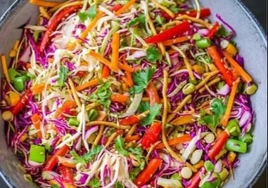Bowl of colorful Asian chopped salad with fresh vegetables and dressing