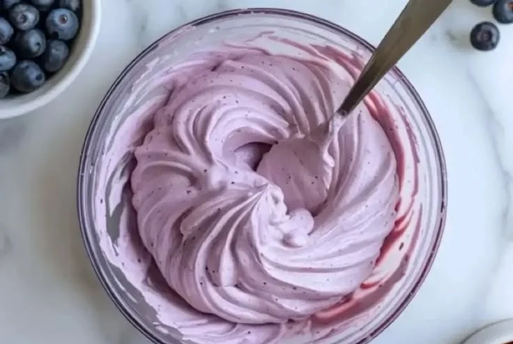 Homemade blueberry cream cheese frosting spread on a cake