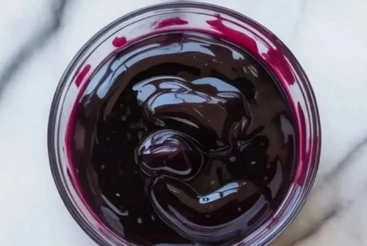 Delicious homemade blueberry curd in a glass jar with fresh blueberries.
