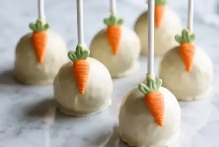 Delicious carrot cake pops arranged on a platter with cream cheese frosting.