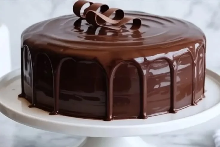 Decadent chocolate cake topped with sour cream frosting and chocolate shavings