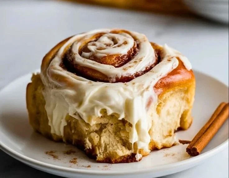 Cream cheese cinnamon roll frosting spread on freshly baked cinnamon rolls