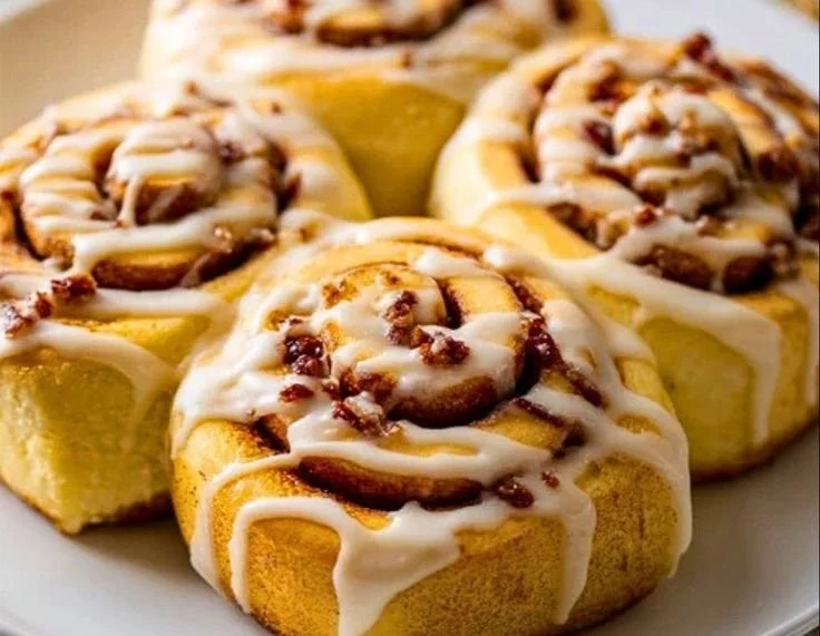 Homemade eggnog cinnamon rolls with icing on a wooden table