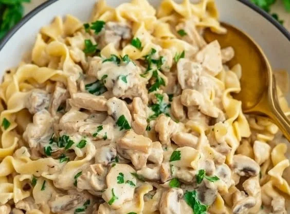 A plate of creamy ground turkey stroganoff served with pasta and fresh herbs