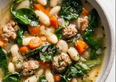 Bowl of Italian Sausage and White Bean Soup garnished with fresh herbs