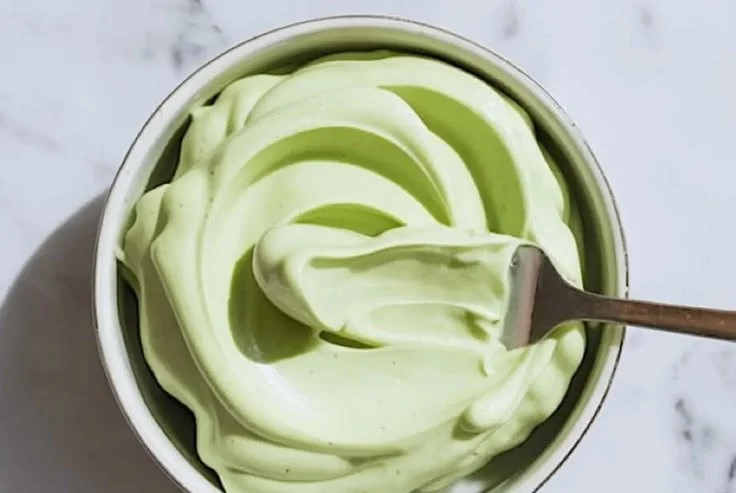 Pistachio Mascarpone cake filling in a mixing bowl with pistachios on the side
