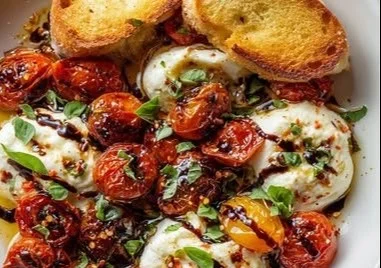 Plate of roasted tomatoes served with creamy burrata cheese