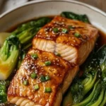 A beautifully plated salmon fillet glazed with miso and butter, garnished with herbs.