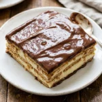 A delicious Eclair Cake topped with chocolate glaze and creamy filling.