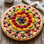 A colorful sliced fruit pizza topped with fresh fruits and cream.