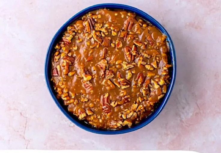 A bowl of creamy pecan pie dip garnished with pecans and served with cookies